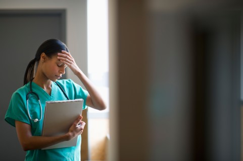 Female nurse with head in hands.