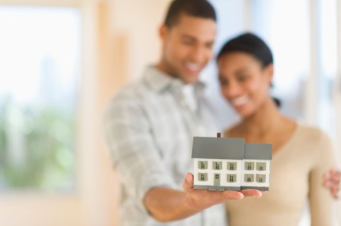 Couple holding toy house.