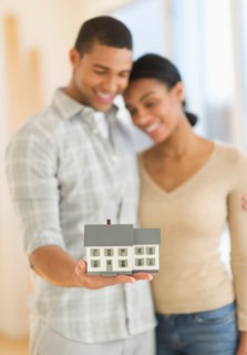 Couple holding toy house.