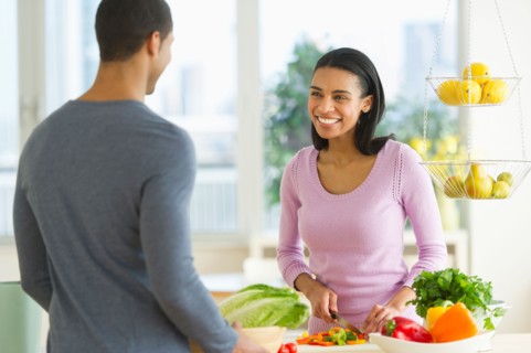 Couple chopping vegetables in kitchen.