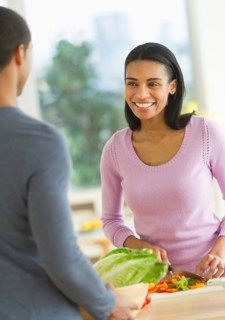 Couple chopping vegetables in kitchen.