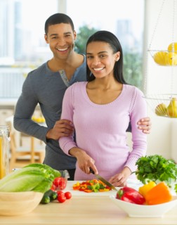 Portrait of couple chopping vegetables in kitchen.