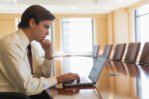Businessman using laptop in board room.