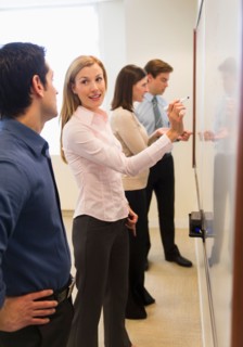 Business people writing at whiteboard.