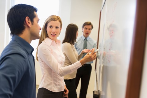 Business people writing at whiteboard.