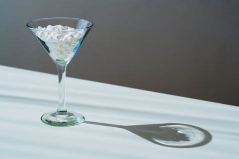 Martini glass filled with pills, studio shot.
