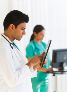 Doctors working on digital tablet and computer.