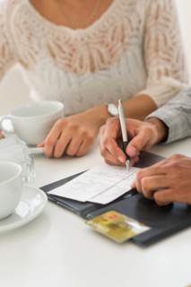 Couple enjoying tea, man signing receipt.