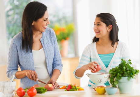 Mother and daughter (12-13) cooking in kitchen.