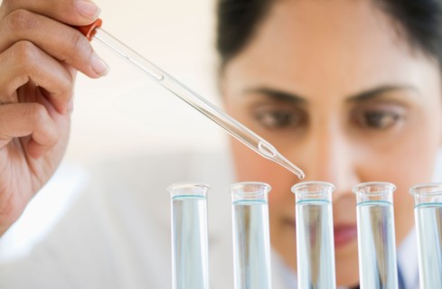Scientist pipetting liquid into test tubes.
