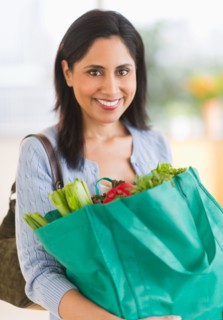 Woman holding bag of fresh vegetables.