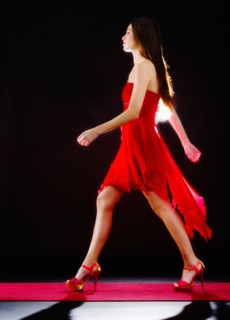 Woman wearing red dress on catwalk.