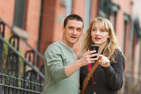 Couple using smart phone on street.