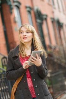 Woman using digital tablet on street.