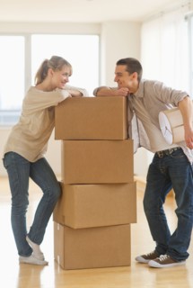 Couple leaning on cardboard boxes during relocation.