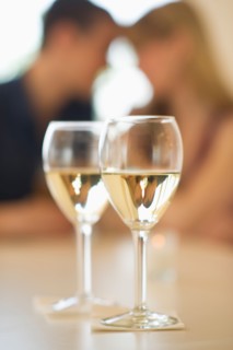 Close up of wine glasses with couple in background.