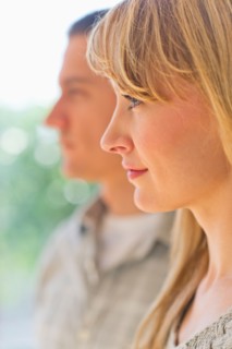 Close up woman's profile with man in background.
