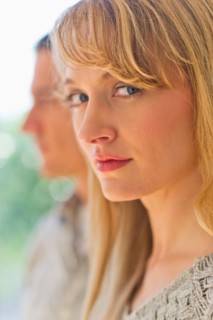Close up woman's face with man in background.