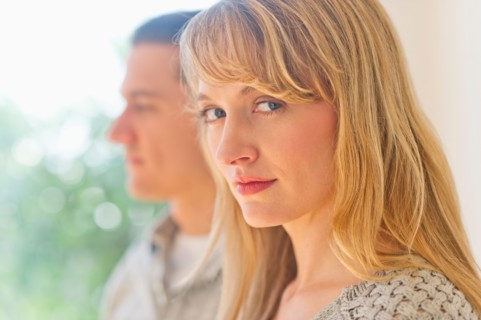 Close up woman's face with man in background.