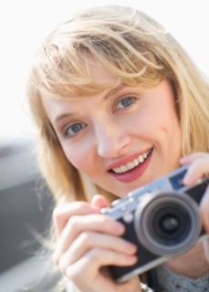 Portrait of smiling woman with camera.