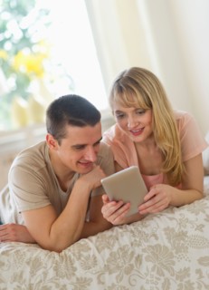 Couple lying on bed and using digital tablet.