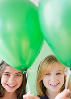 Two girls holding green balloons. Photo : Jamie Grill