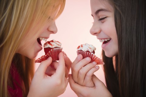 Close up of two girls eating cupcakes. Photo : Jamie Grill