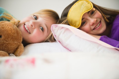 Two girls lying in bed. Photo : Jamie Grill