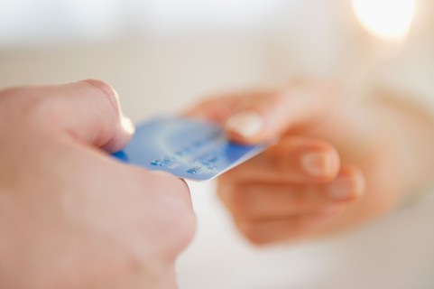 Close up of man's and woman's hands holding credit card. Photo : Jamie Grill