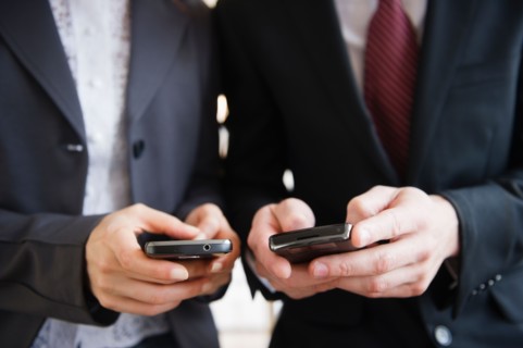 Close up of business people's hand texting on mobile phones. Photo : Jamie Grill
