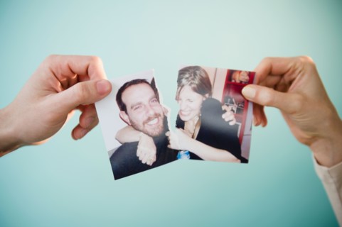 Close up of man's and woman's hands holding torn photograph of themselves,  studio shot. Photo :