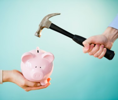 Close up of man's and woman's hands holding piggy bank and hammer,  studio shot. Photo : Jamie