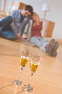 Close up of wine glasses on floor with couple behind. Photo : Daniel Grill