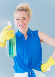 Portrait of young woman spraying cleaning detergent, studio shot. Photo : Daniel Grill