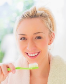 Portrait of smiling young woman with toothbrush. Photo : Daniel Grill