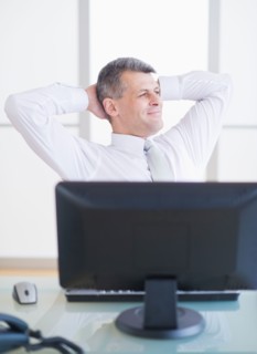 Portrait of businessman relaxing at desk. Photo : Daniel Grill