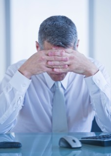 Portrait of depressed businessman sitting at desk. Photo : Daniel Grill
