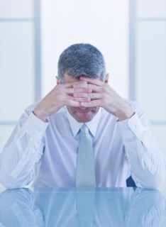 Portrait of depressed businessman sitting at desk. Photo : Daniel Grill