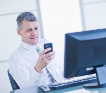 Man with mobile phone sitting in office. Photo : Daniel Grill