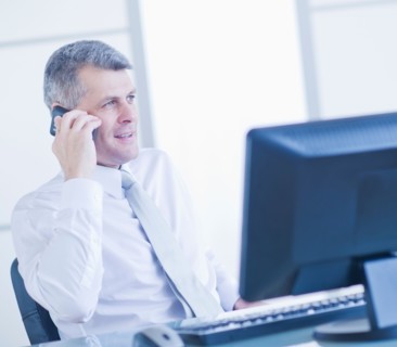 Man with mobile phone sitting in office. Photo : Daniel Grill
