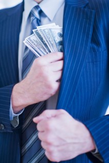 Businessman hiding banknotes in pocket. Photo : Daniel Grill