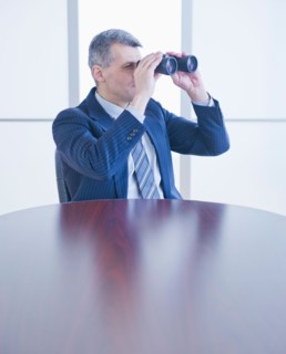 Portrait of businessman holding binoculars. Photo : Daniel Grill