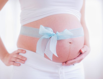 Pregnant woman with blue ribbon on her belly. Photo : Daniel Grill