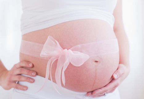 Pregnant woman with pink ribbon on her belly. Photo : Daniel Grill