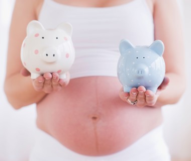 Pregnant woman holding two piggybanks. Photo : Daniel Grill