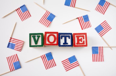 Studio shot of small american flags and wooden blocks with text VOTE . Photo : Winslow Productions