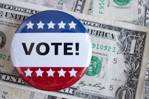 Studio shot of vote pin and one dollar banknotes. Photo : Winslow Productions