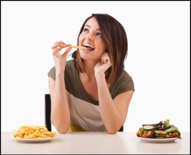 Young woman choosing between healthy and unhealthy food. Photo : Mike Kemp