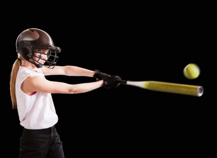 Girl (12-13) plying softball, studio shot. Photo : Mike Kemp