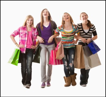 Studio shot of four happy girls (12-13) with shopping bags. Photo : Mike Kemp
